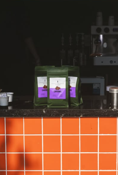 Pacotes de café da torrefação sobre o balcão de azulejos laranja